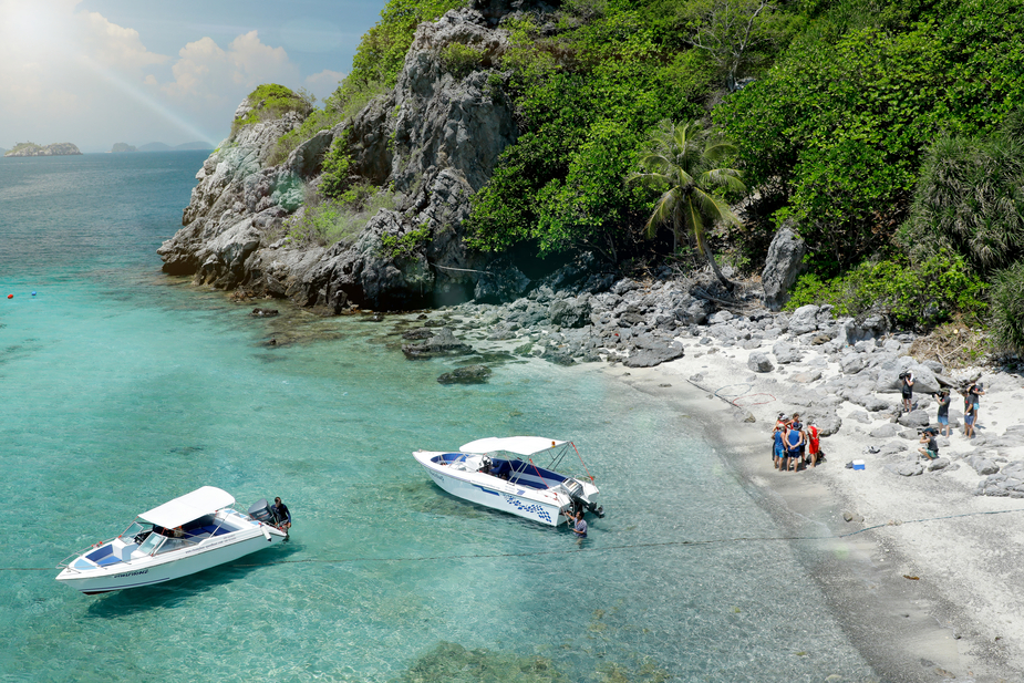 Film crew arriving by speedboat at a tropical island in Thailand – a popular filming location with dramatic limestone cliffs and turquoise waters.